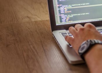 노트북 화면에 CSS 코드를 작성 중인 개발자의 손
