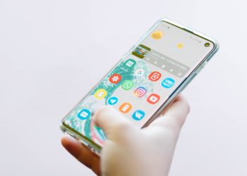 다양한 앱 아이콘이 설치된 스마트폰 홈화면을 손으로 사용하는 모습