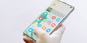 다양한 앱 아이콘이 설치된 스마트폰 홈화면을 손으로 사용하는 모습