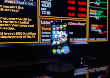 Smartphone displaying AI apps in front of a financial data screen in London.