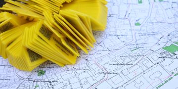 Stack of yellow QR code markers placed on a detailed map for location tracking and navigation.