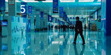 An indoor view of a busy conference hall during World Summit 2020 with directional signs and reflections.