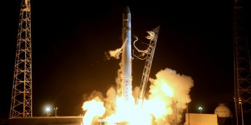 Modern shuttle spaceship launching from station against dark night sky and beginning mission