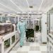 Scientist in protective gear walking in a high-tech cleanroom laboratory environment.