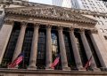 Iconic neoclassical facade of the New York Stock Exchange with American flags.