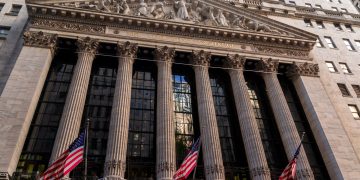 Iconic neoclassical facade of the New York Stock Exchange with American flags.