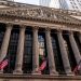 Iconic neoclassical facade of the New York Stock Exchange with American flags.