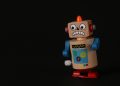 A vibrant wooden toy robot stands on a dark surface, showcasing vivid colors and playful design.