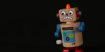 A vibrant wooden toy robot stands on a dark surface, showcasing vivid colors and playful design.