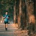 An athletic man runs along a picturesque tree-lined street during autumn. Perfect for fitness and outdoor themes.