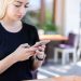 Young woman in a black shirt texting on her smartphone at an outdoor cafe.