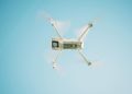 A sleek white drone flying under a clear blue sky, capturing aerial views.