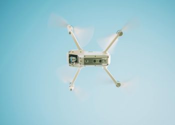A sleek white drone flying under a clear blue sky, capturing aerial views.