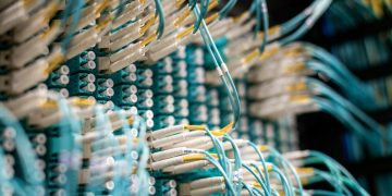 From below of fiber optic switch with sockets and connected rubber cables on blurred background