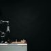 An articulated robotic arm competes in chess on a board against a dark background, highlighting AI and innovation.