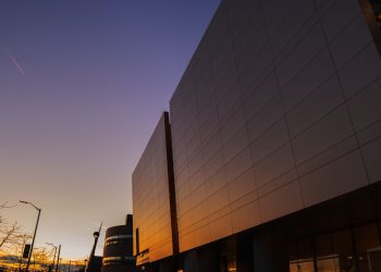 Stunning modern building exterior reflecting sunset light, urban skyline view.