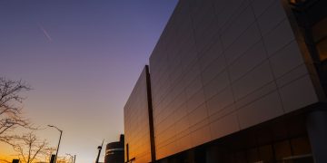 Stunning modern building exterior reflecting sunset light, urban skyline view.