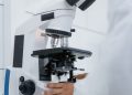 Detailed view of a scientist operating a microscope in a laboratory setting.