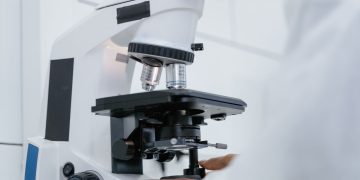 Detailed view of a scientist operating a microscope in a laboratory setting.