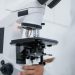 Detailed view of a scientist operating a microscope in a laboratory setting.