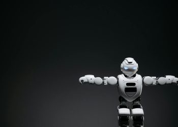 Studio shot of a humanoid robot with glowing eyes against a dark background, offering ample copyspace.