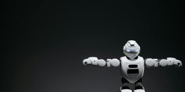 Studio shot of a humanoid robot with glowing eyes against a dark background, offering ample copyspace.