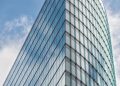 A sleek glass skyscraper reflecting the blue sky and clouds, showcasing modern architectural design.