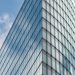 A sleek glass skyscraper reflecting the blue sky and clouds, showcasing modern architectural design.