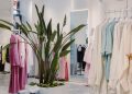 Bright and airy boutique featuring pastel garments and a lush green plant centerpiece.
