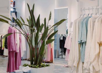 Bright and airy boutique featuring pastel garments and a lush green plant centerpiece.