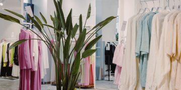 Bright and airy boutique featuring pastel garments and a lush green plant centerpiece.