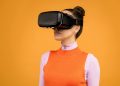 Woman enjoying virtual reality with VR headset against vibrant orange background.