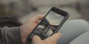 Close-up of hands holding a smartphone showing a mountain scene, captured outdoors in Banff.