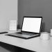 A modern minimalistic desk setup with a laptop, ceramic cup, and candle for a serene workspace.
