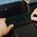 Closeup of hands typing on an RGB keyboard in a modern office setting.