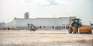 A large construction site featuring heavy machinery and industrial building in progress.