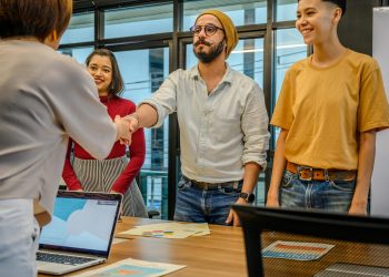 Colleagues shaking hands during a business meeting in a modern office setting.