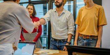 Colleagues shaking hands during a business meeting in a modern office setting.