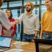 Colleagues shaking hands during a business meeting in a modern office setting.