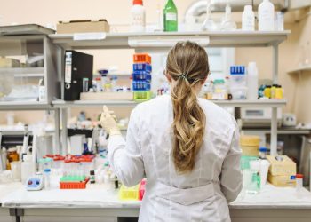 A female scientist conducting research in a well-equipped laboratory, focusing on chemical analysis.