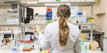 A female scientist conducting research in a well-equipped laboratory, focusing on chemical analysis.