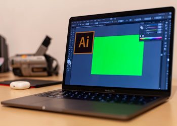 Close-up of a MacBook Pro with Adobe Illustrator open on a desk, showcasing creative workspace essentials.