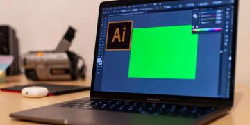 Close-up of a MacBook Pro with Adobe Illustrator open on a desk, showcasing creative workspace essentials.
