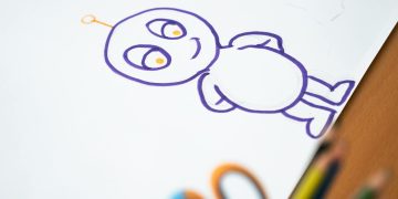 Colorful cartoon character sketch on paper with colored pencils on the side.