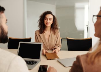 A woman in a business suit participates in a job interview, showcasing professionalism and modern office environment.