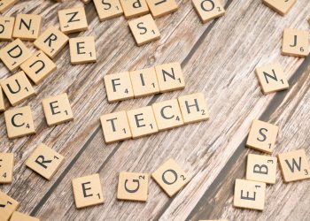 Fintech spelled out with wooden letter tiles on a rustic wooden background.