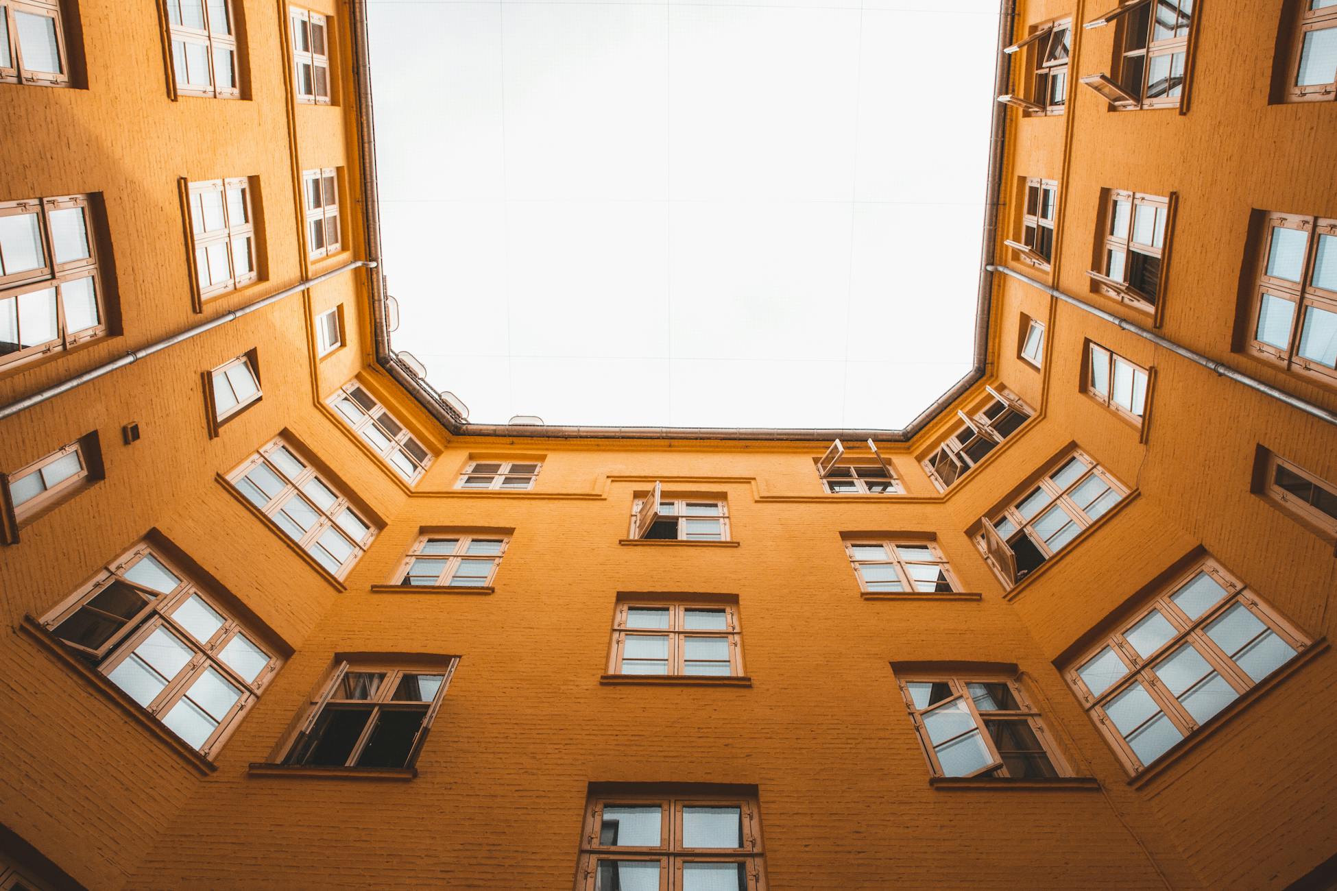 A low angle view of a yellow multi-storey building courtyard in Copenhagen, Denmark.