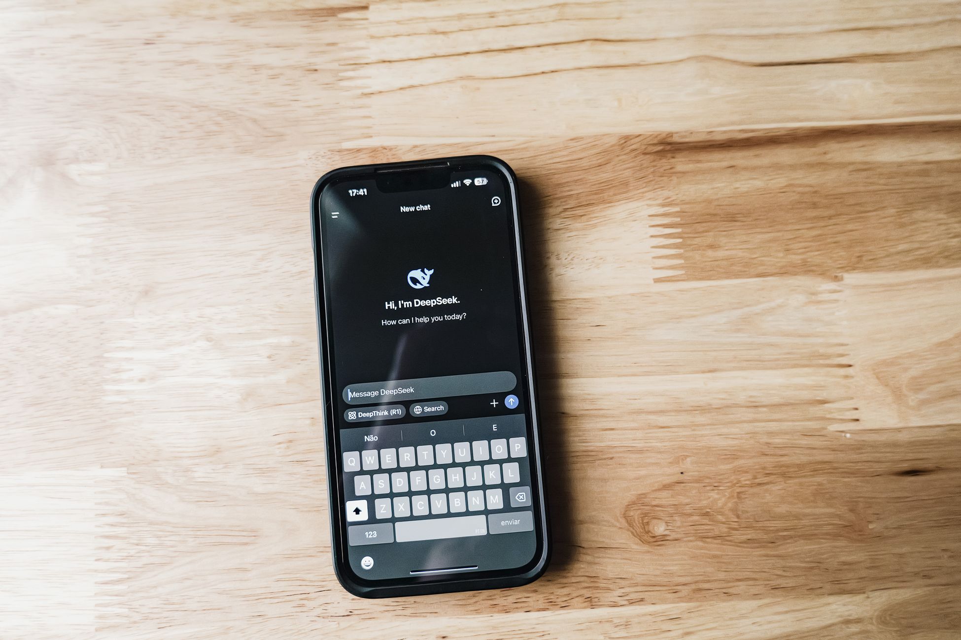 Close-up of a smartphone displaying AI chat interface on a wooden table.