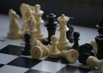 Close-up of scattered chess pieces on a black and white board.