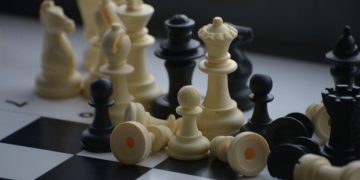 Close-up of scattered chess pieces on a black and white board.